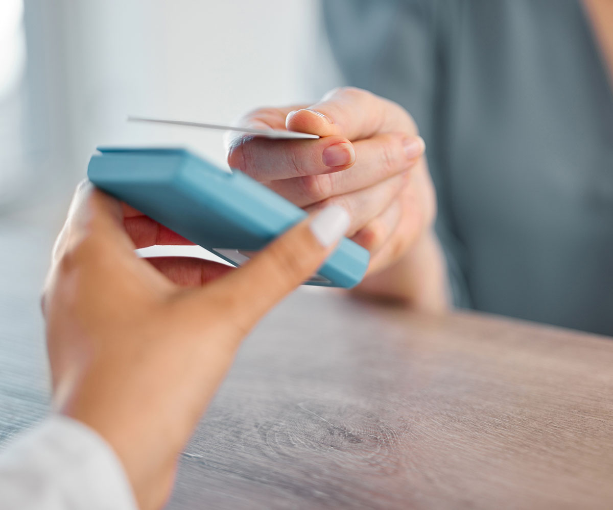 Eine Person hält eine E-Card an ein Lesegerät 